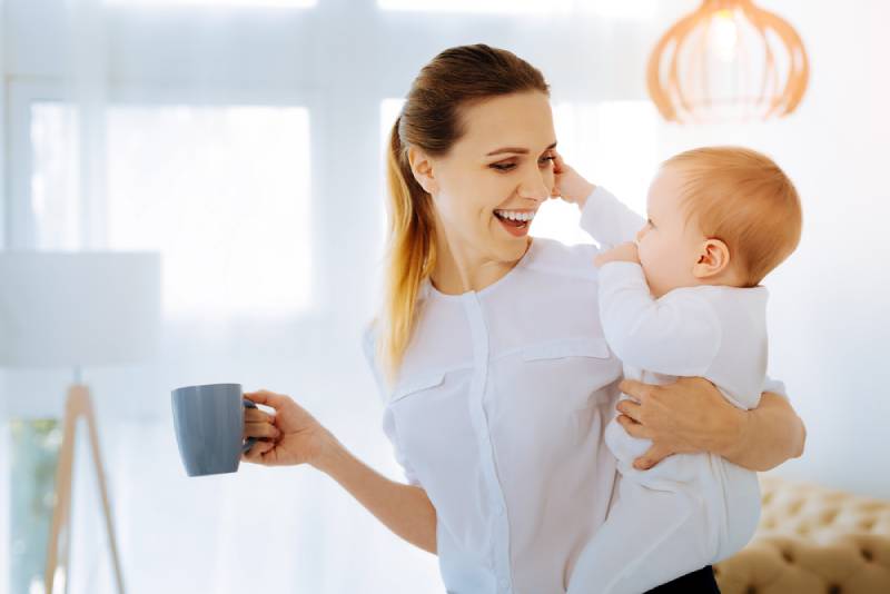 Frau hält Baby und Teetasse