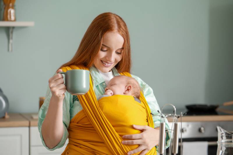 Frau hält Baby und trinkt Tee