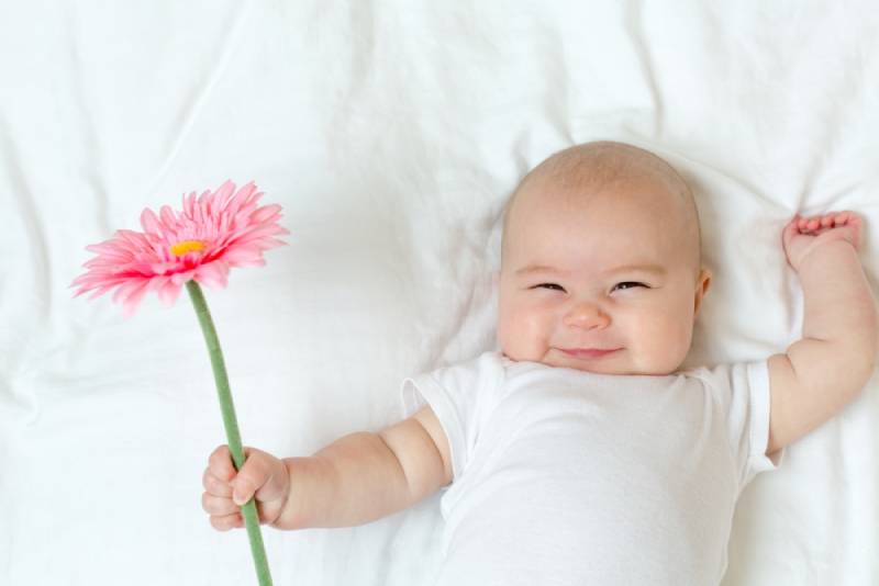 lustiges Baby, das eine Blume hält
