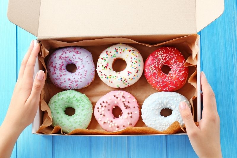 Frau, die Box mit bunten Donuts hält