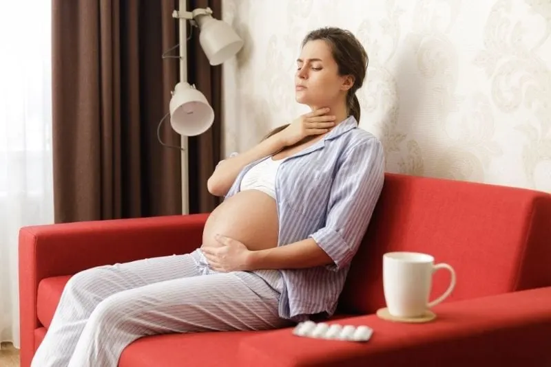 Junge schwangere Frau mit Halsschmerzen