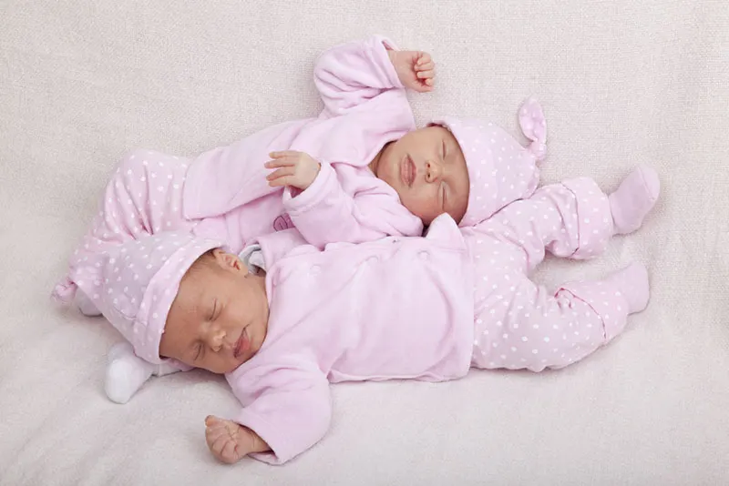 Zwillingsbabys tragen rosa Kleidung und schlafen