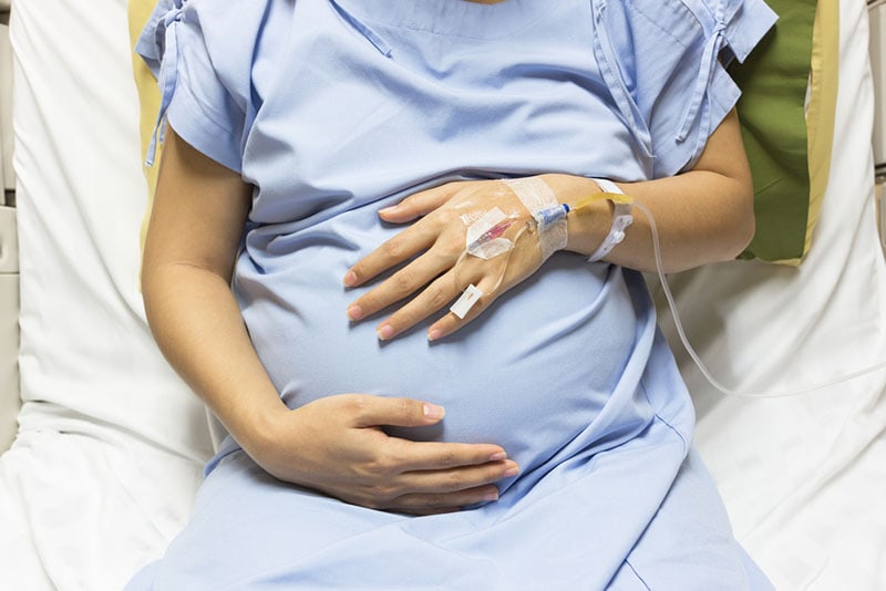 schwangere Frau im Krankenhausbett liegend