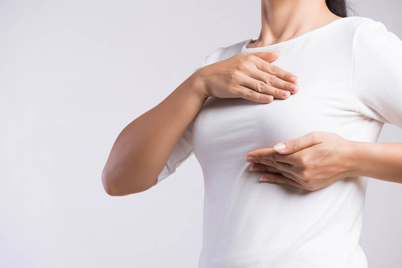 Frau im weißen Hemd überprüft ihre Brust