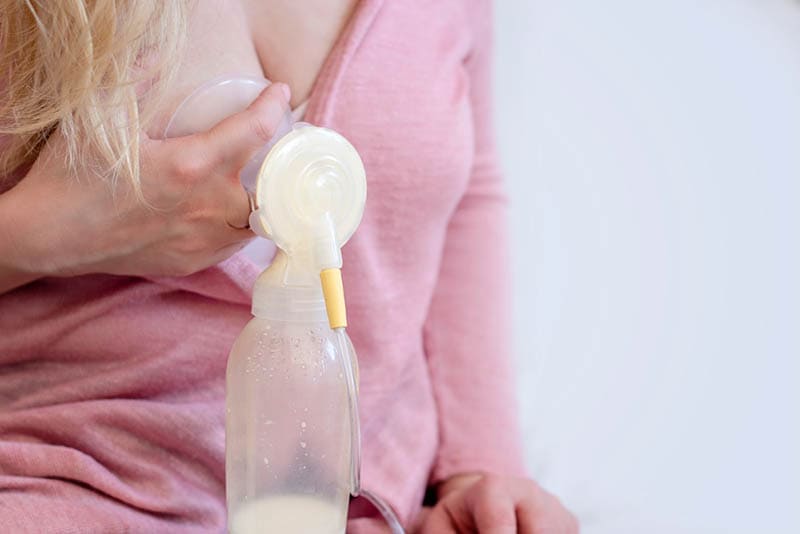 Frau mit blonden Haaren pumpt ihre Muttermilch