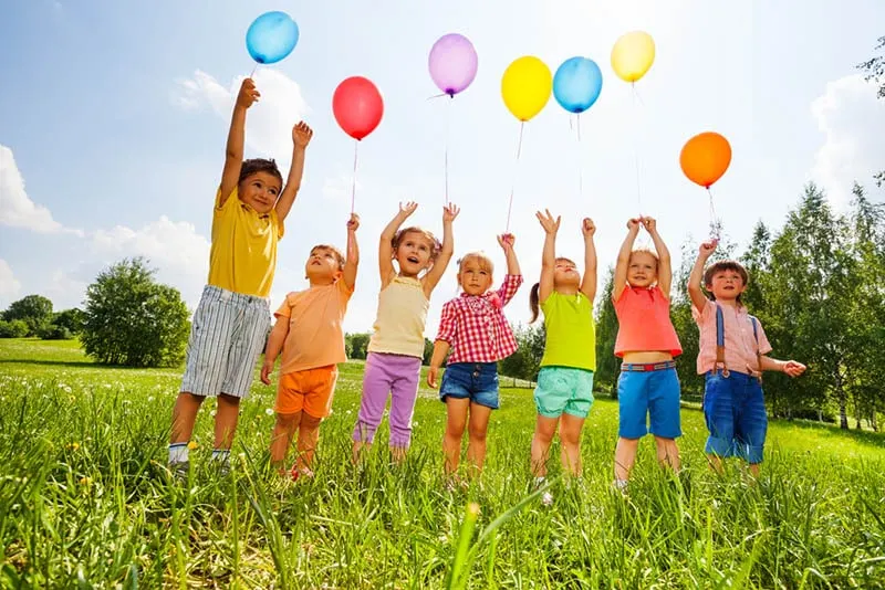 Kinder, die mit Luftballons auf dem Feld stehen