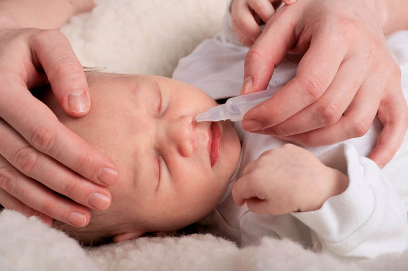 Neugeborenes bekommt Nasentropfen für laufende Nase
