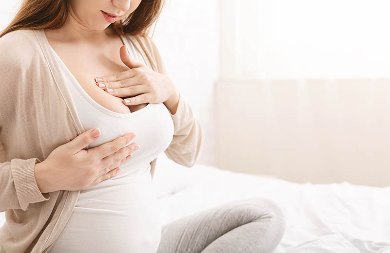 eine schwangere Frau berührt ihre wunden Brüste