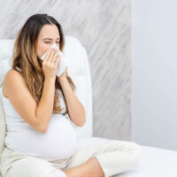 kranke schwangere Frau mit verstopfter Nase