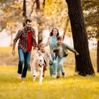 glückliche Familie, die mit Hund läuft