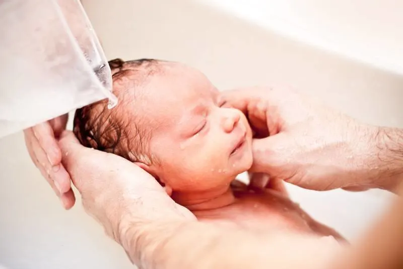 junge Eltern baden ihr Neugeborenes