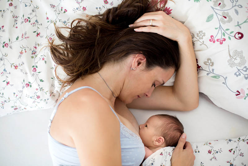 junge Mutter stillt ihr Baby im Bett