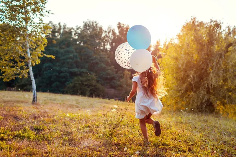 kleines Mädchen läuft mit Luftballons