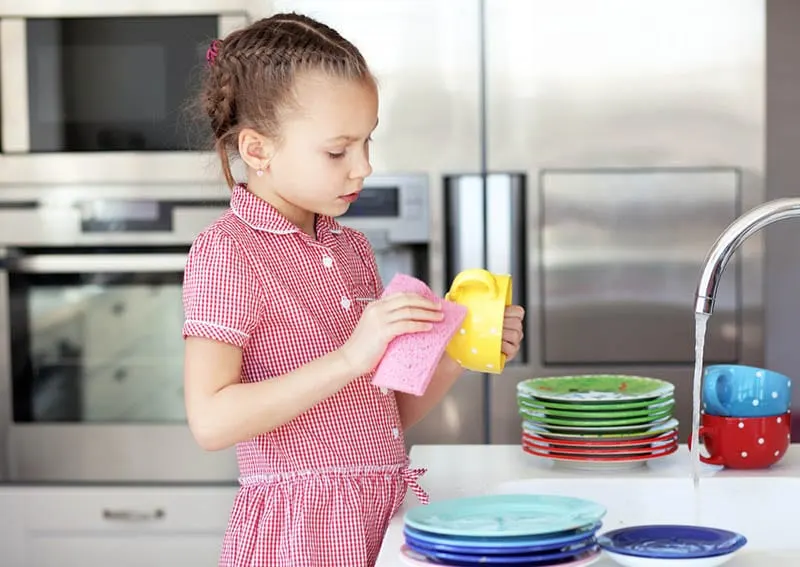 süßes kleines Mädchen das Geschirr spülen