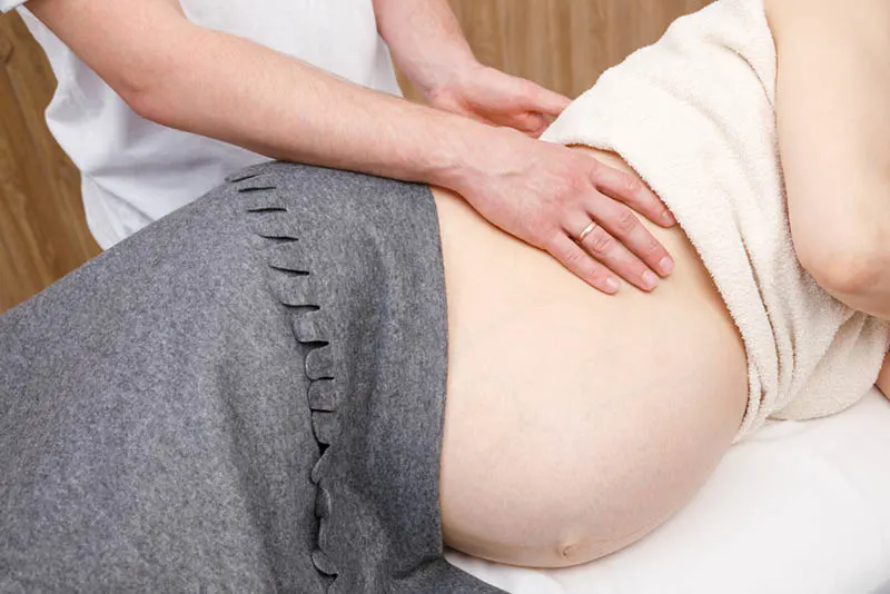 Arzt, der einer schwangeren Frau während der Wehen Massage gibt