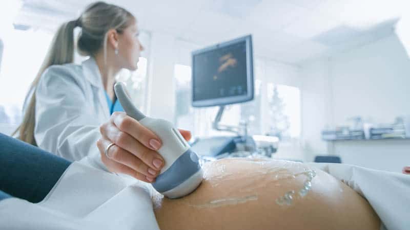 Arzt macht Ultraschalluntersuchung der schwangeren Frau, um die Position des Babys zu überprüfen