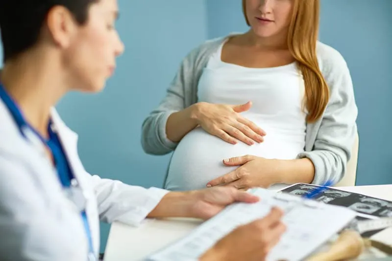 Arzt untersucht schwangere Frau im Krankenhausbüro