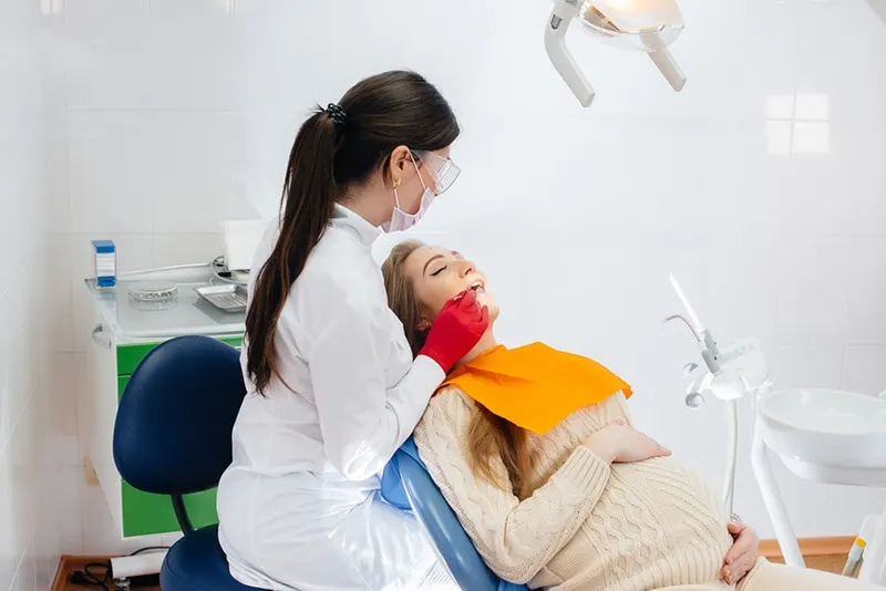 Ein professioneller Zahnarzt behandelt und untersucht eine schwangere Frau in einer modernen Zahnarztpraxis