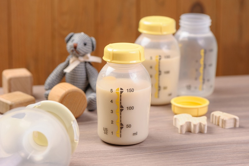 Flaschen Muttermilch und Babyspielzeug auf der Registerkarte
