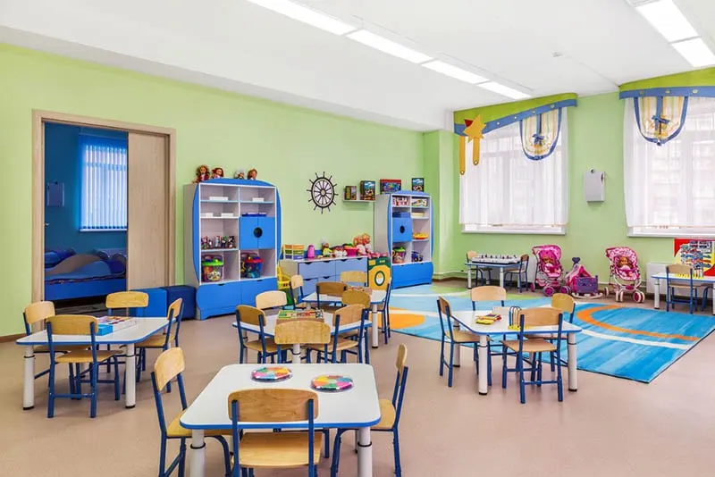 Kindergartenraum voller Tische und Stühle für Kinder und Spiele