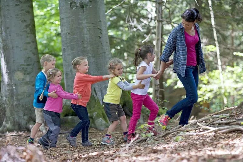 Lehrer geht mit Kindern im Waldkindergarten spazieren