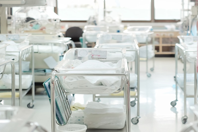 Nicht identifizierte Neugeborene, die im Bett Stubenwagen im modernen Entbindungsheim liegen