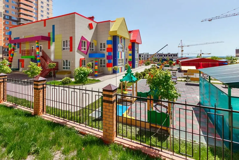 buntes Kindergartengebäude mit Spielplätzen im Hof