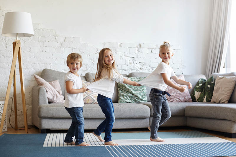 drei entzückende Kinder, die zusammen im Wohnzimmer spielen