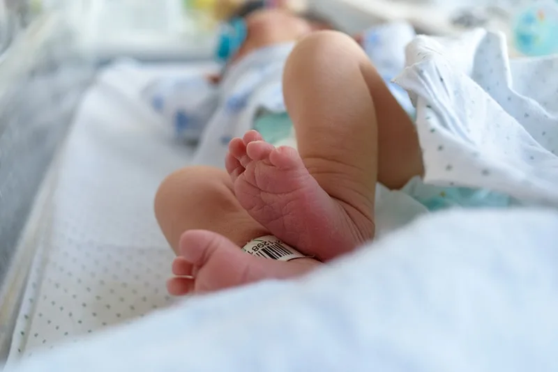 entzückendes neugeborenes Baby, das in Windeln im Babybett des Krankenhauses liegt