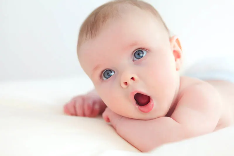erstaunliches Baby mit großen blauen Augen, die seinen Mund offen halten