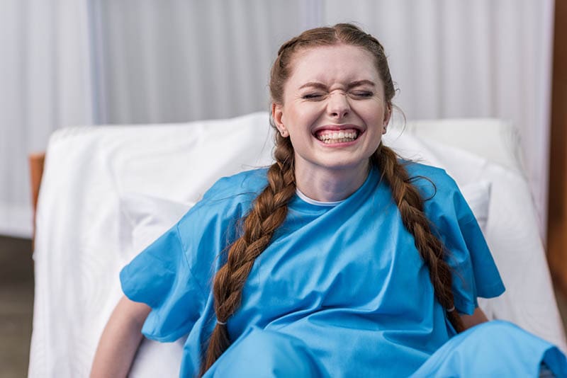 junge Frau mit großen Schmerzen bei der Geburt eines Babys auf einem Krankenhausbett