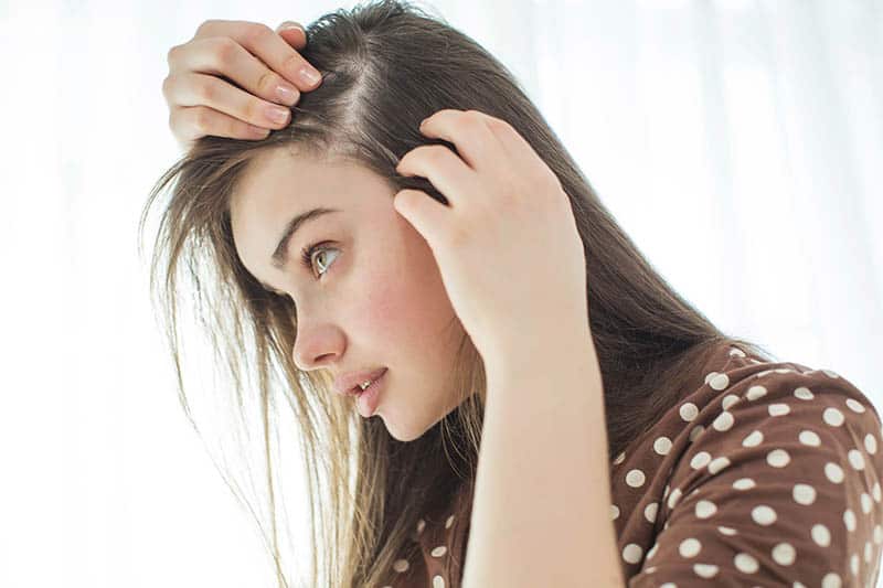 junge ernsthafte Frau, die ihre Haarausfall prüft