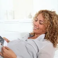 lächelnde schwangere Frau, die Sonogramm des Babys betrachtet