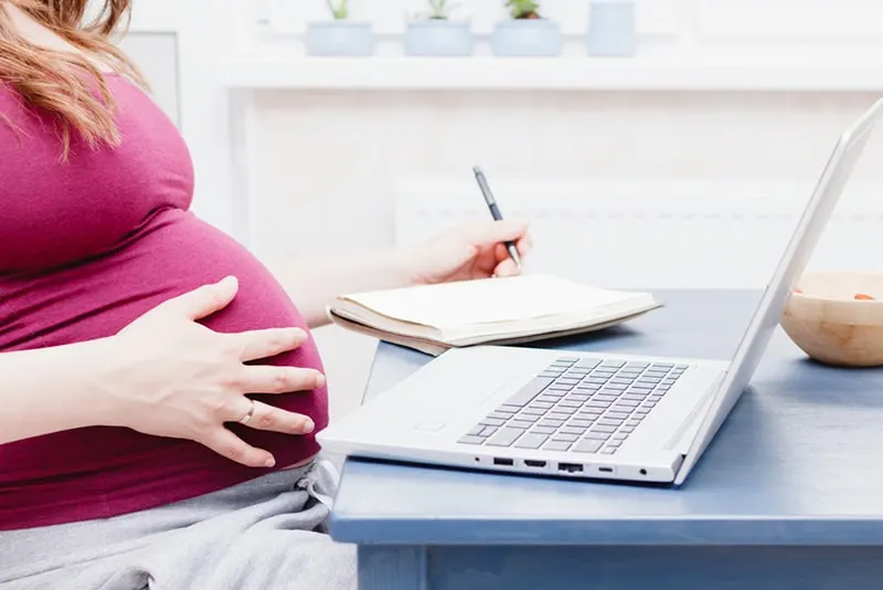 schwangere Frau, die am Tisch sitzt und Finanzen berechnet
