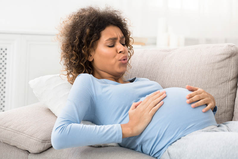 schwangere Frau, die tief atmet, während sie Kontraktionen auf der Couch hat