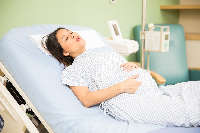 schwangere Frau mit Wehen auf Krankenhausbett
