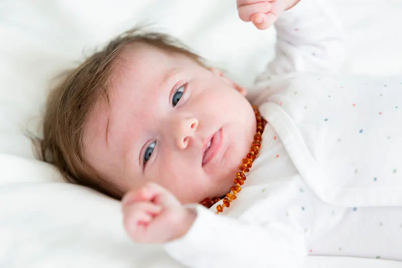 süßes Baby, das Bernsteinkette gegen Kinderkrankheiten trägt