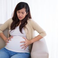 schwangere Frau mit Kontraktionen auf der Couch