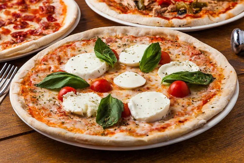 Authentische italienische Pizza mit Mozzarella-Käse, Basilikum und Kirschtomaten, serviert auf einem Teller