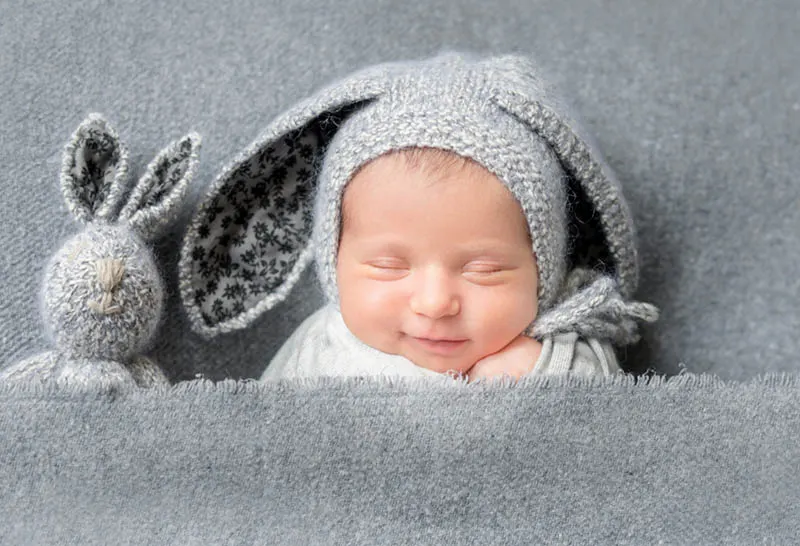 Baby-Junge trägt Hasenmütze und lächelnd beim Schlafen mit Hase