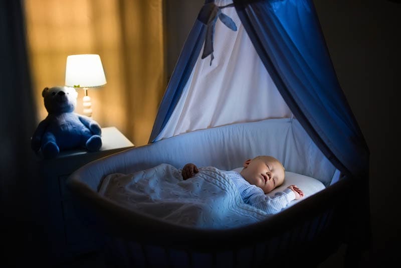 Baby schläft fest in einem Kinderbett mit Baldachin in der Nacht im Schlafzimmer