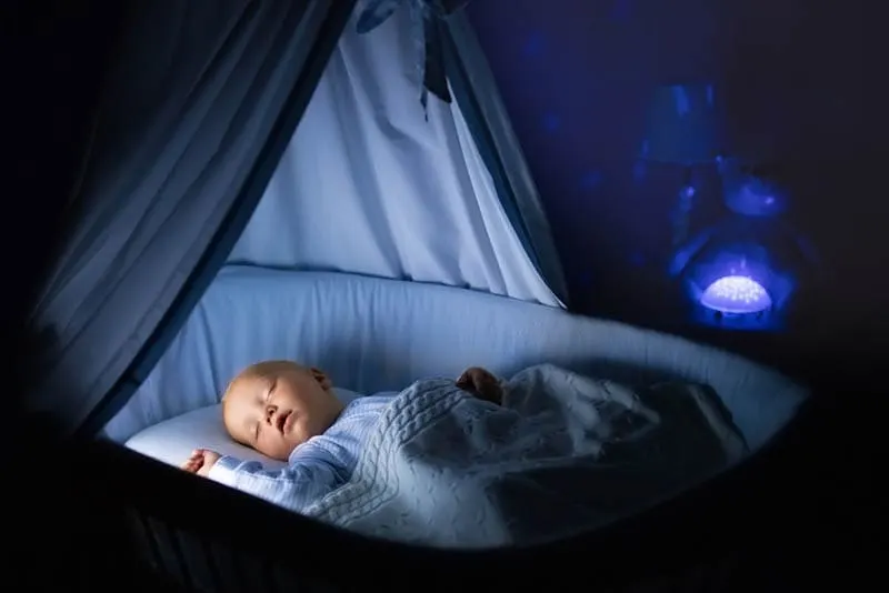 Babyjunge schläft nachts in einem Kinderbett mit