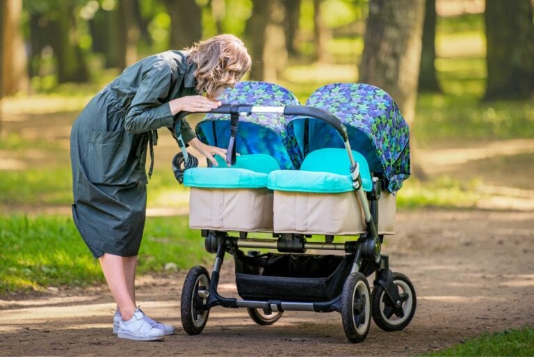Mutter steht neben Zwillingskinderwagen