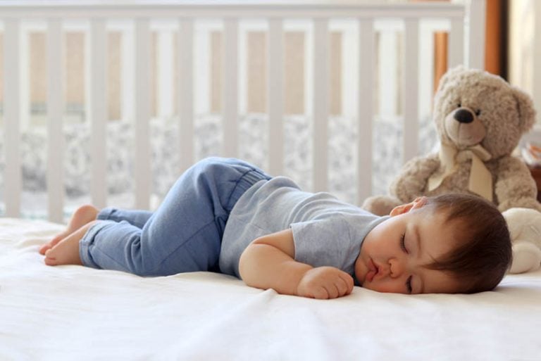 süßes Baby, das auf Bauch im Schlafzimmer schläft