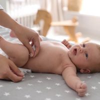 Mutter wechselt Windel zu Baby auf dem Bett zu Hause