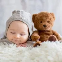 liebenswertes Baby lächelnd beim Schlafen mit Teddybär