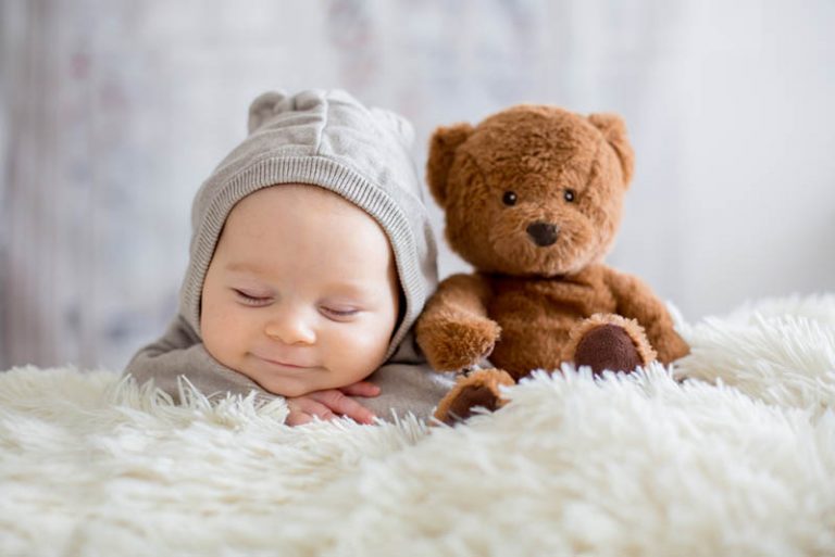 liebenswertes Baby lächelnd beim Schlafen mit Teddybär