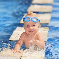 süßes Baby mit Schwimmbrille im Pool