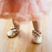 süßes Baby, das rosa Rock und goldene Schuhe trägt