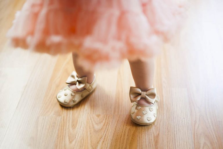 süßes Baby, das rosa Rock und goldene Schuhe trägt